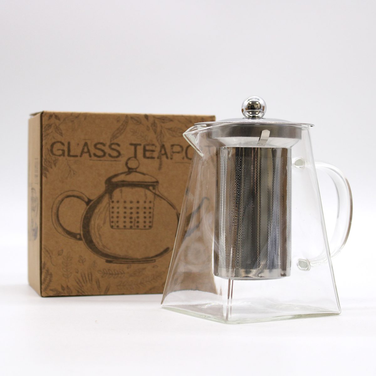 A glass teapot with a metal infuser sits beside a box labeled "GLASS TEAPOT." The box features an illustration of a teapot design, resting on a white background.