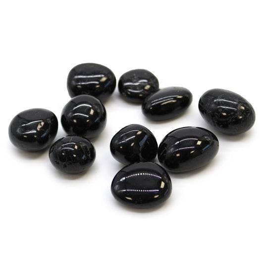 A scattering of ten shiny, black, tumbled stones rests on a clean, white surface.