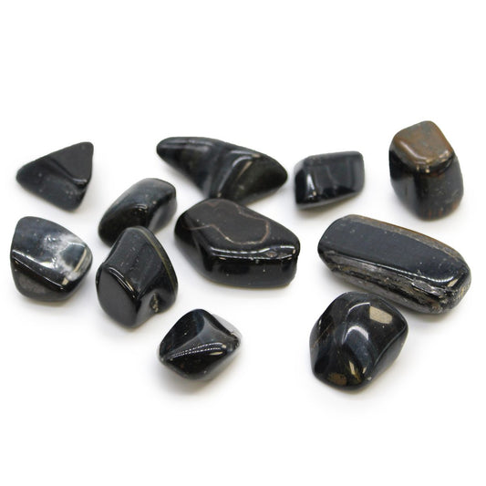 Several tumbled obsidian stones are scattered, reflecting light on their glossy, black surfaces. The stones are seen against a plain white background.