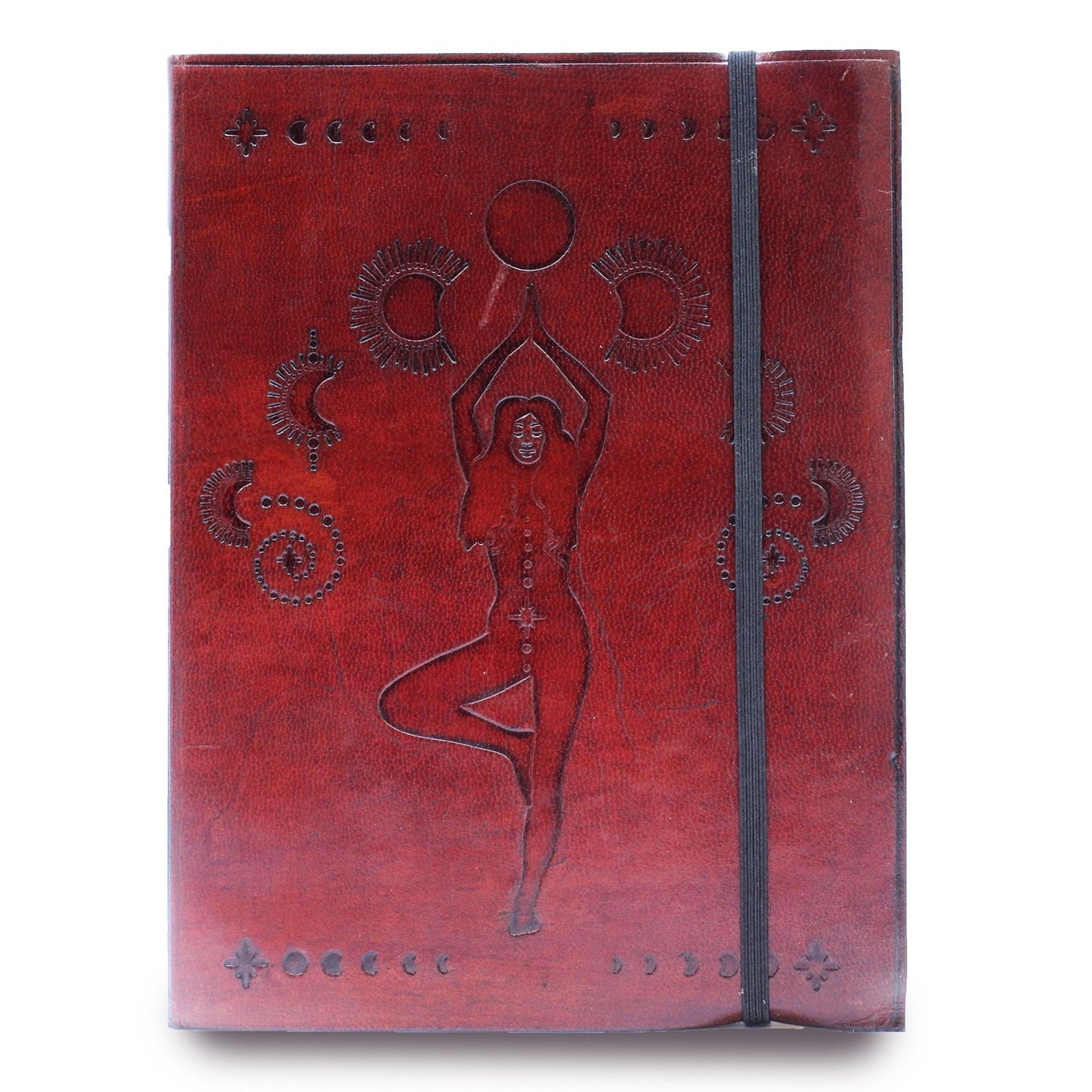 A reddish-brown journal shows an embossed woman in tree pose, holding a circle, decorated with moon phases and sunbursts. A black elastic strap lies vertically across the front cover.