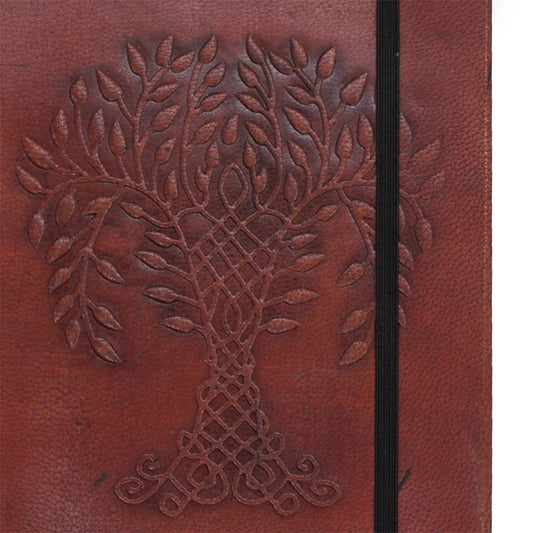 A brown leather notebook displays an embossed Celtic tree with a visible black elastic closure.