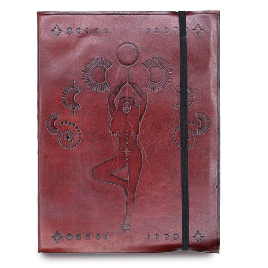 A red, leather-bound journal is seen against a white background. A woman in a yoga pose is embossed in the center surrounded by suns, moons, and other celestial symbols. A black elastic band stretches from the top to the bottom of the journal.