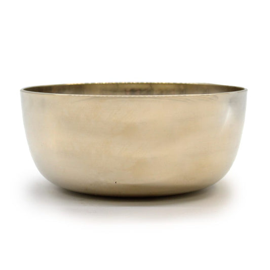 A smooth brass bowl sits on a white surface, slightly reflective, with a simple, rounded design and a polished finish, suitable for decoration or functional use.