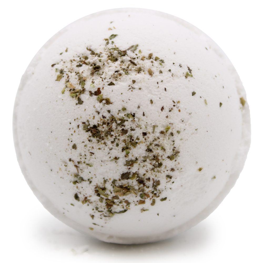 A round, white bath bomb with scattered green and brown herb-like specks rests against a plain white background.