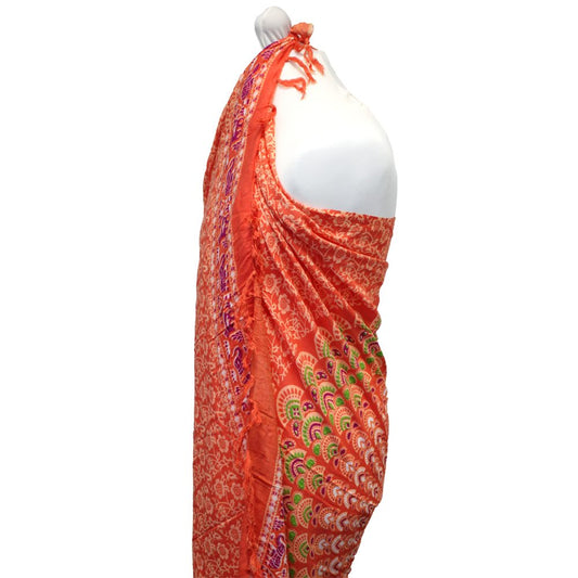 An orange sarong, draped on a mannequin, displays a floral and peacock-eye pattern.