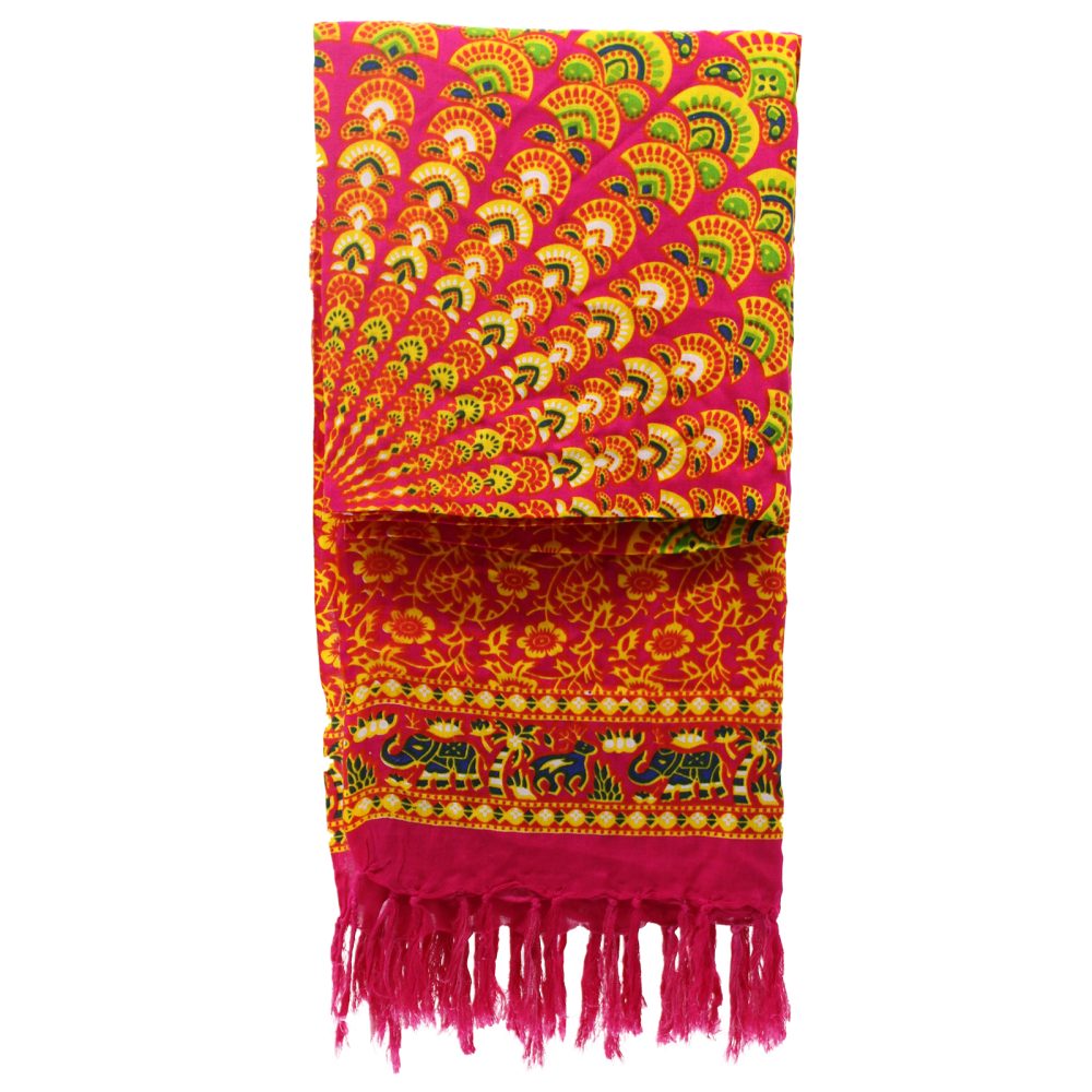 A pink textile with yellow and orange floral and elephant patterns is folded, showing a fringed bottom edge against a white background.