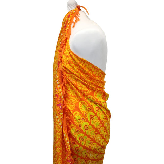 An orange sarong with yellow and pink mandala designs drapes over a white mannequin against a white background.