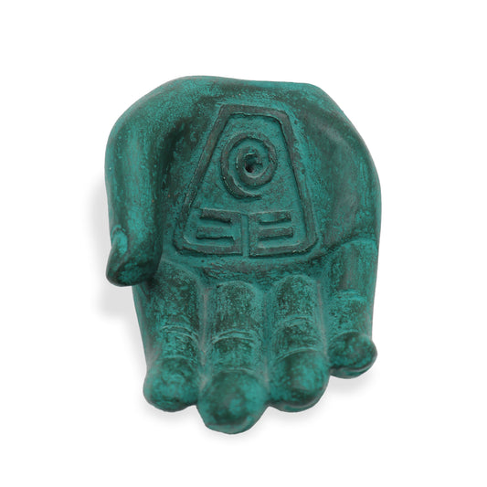 A green, open hand sculpture features a spiral and geometric symbols on the palm. The context is a plain white background, emphasizing its intricate carvings.