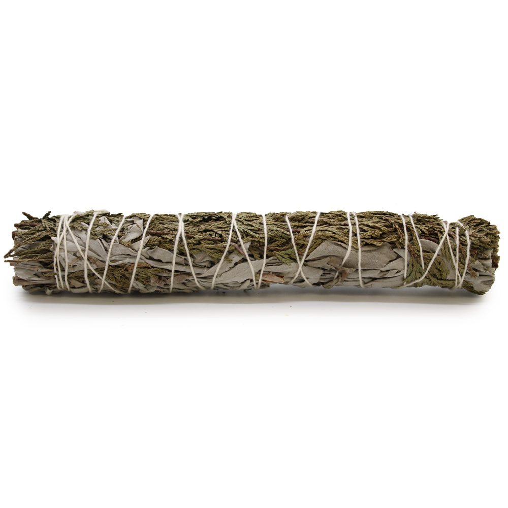 A bundle of dried sage and cedar is wrapped with white string and sits horizontally in the center of a white background.