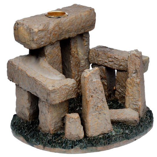 Stonehenge-like structure with a candle holder on top, made of textured, brown rocks. The arrangement of the stones suggests an ancient monument, surrounded by a textured green base.