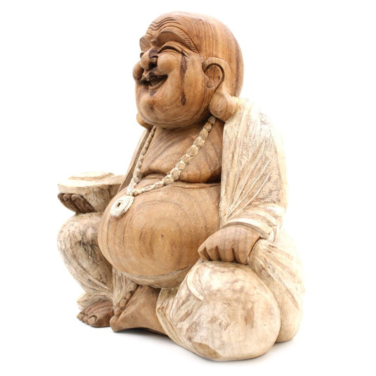 A wooden statue of a laughing, seated figure holding a bowl, wearing a beaded necklace, draped in a robe. The figure's expression is joyful, set against a plain background.