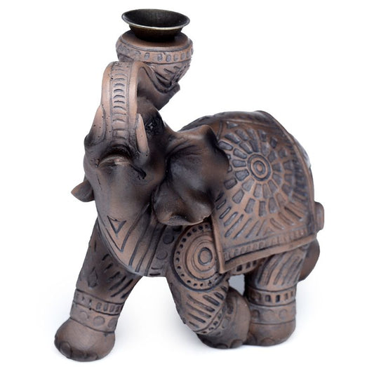 A bronze elephant figurine with decorative patterns holds a small candle holder on its upward-curving trunk, set against a plain white background.