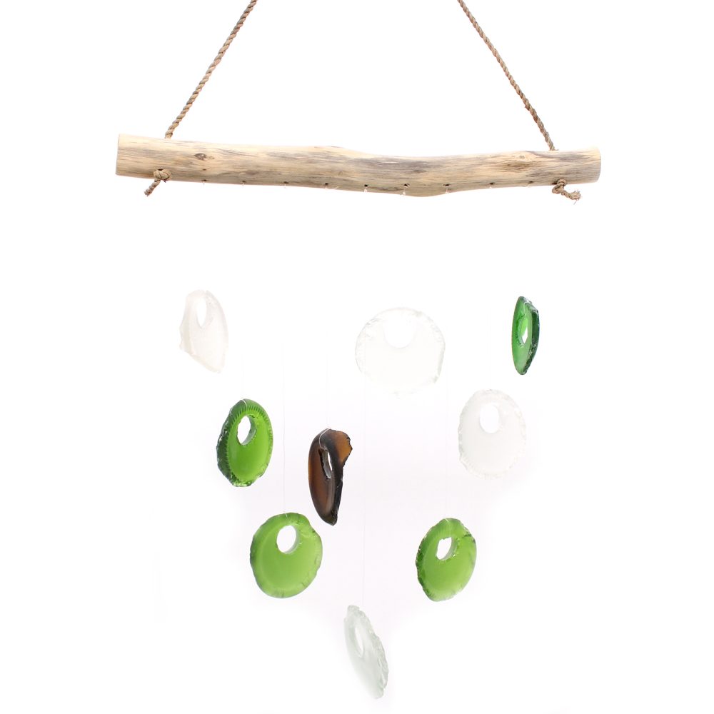 A driftwood branch hangs from twine, supporting a mobile of various-sized, circular glass pieces in green, white, and brown.