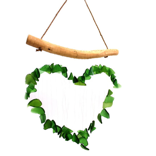 A heart-shaped wind chime, made of green glass pieces, hangs from a curved wooden piece.