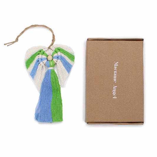 Heart-shaped macramé angel ornament hangs from a jute loop showing blue green and cream fibers with a wooden bead beside a brown box labeled "Macrame Angel" on a white background.
