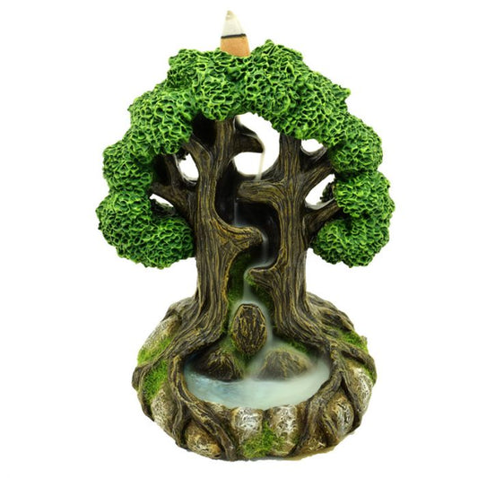 A miniature tree sculpture depicts two intertwined trees with lush green canopies, channeling smoke down a central path into a small pond at their roots.