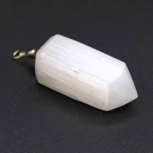 A white, layered crystal point, mounted with a metal loop, lays on a matte black surface.