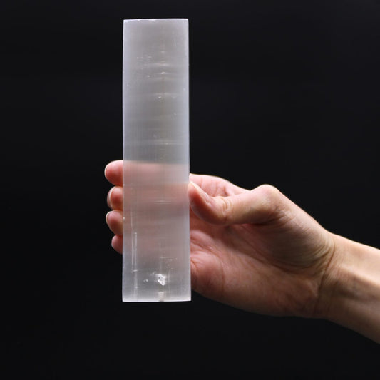 A hand holds a translucent, cylindrical, solid object. The object has imperfections visible within it, and the background is a solid black.