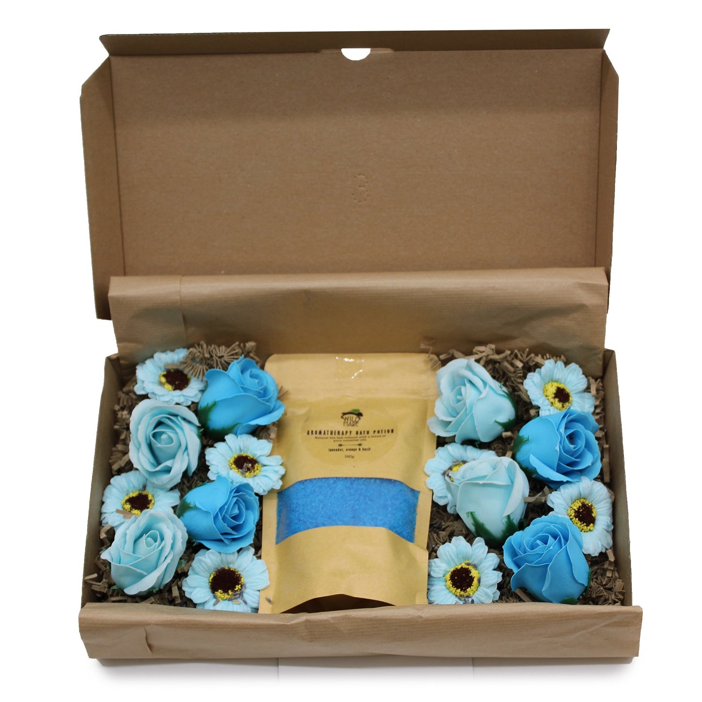 Open brown cardboard box displaying a bag labeled "AROMATHERAPY BATH POTION Natural sea salt infused with a blend of lavender, orange & basil 360g" surrounded by blue roses and daisies atop crinkled paper.