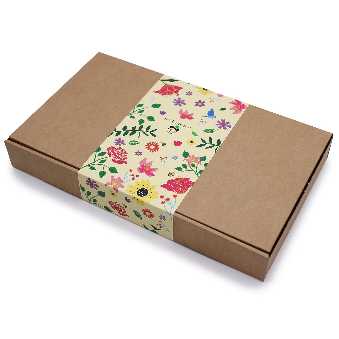 A brown cardboard box sits diagonally on a white surface, secured by a decorative paper band. The band reads "Salt & Flowers by WILD HARE," and is adorned with colorful flowers and illustrations.