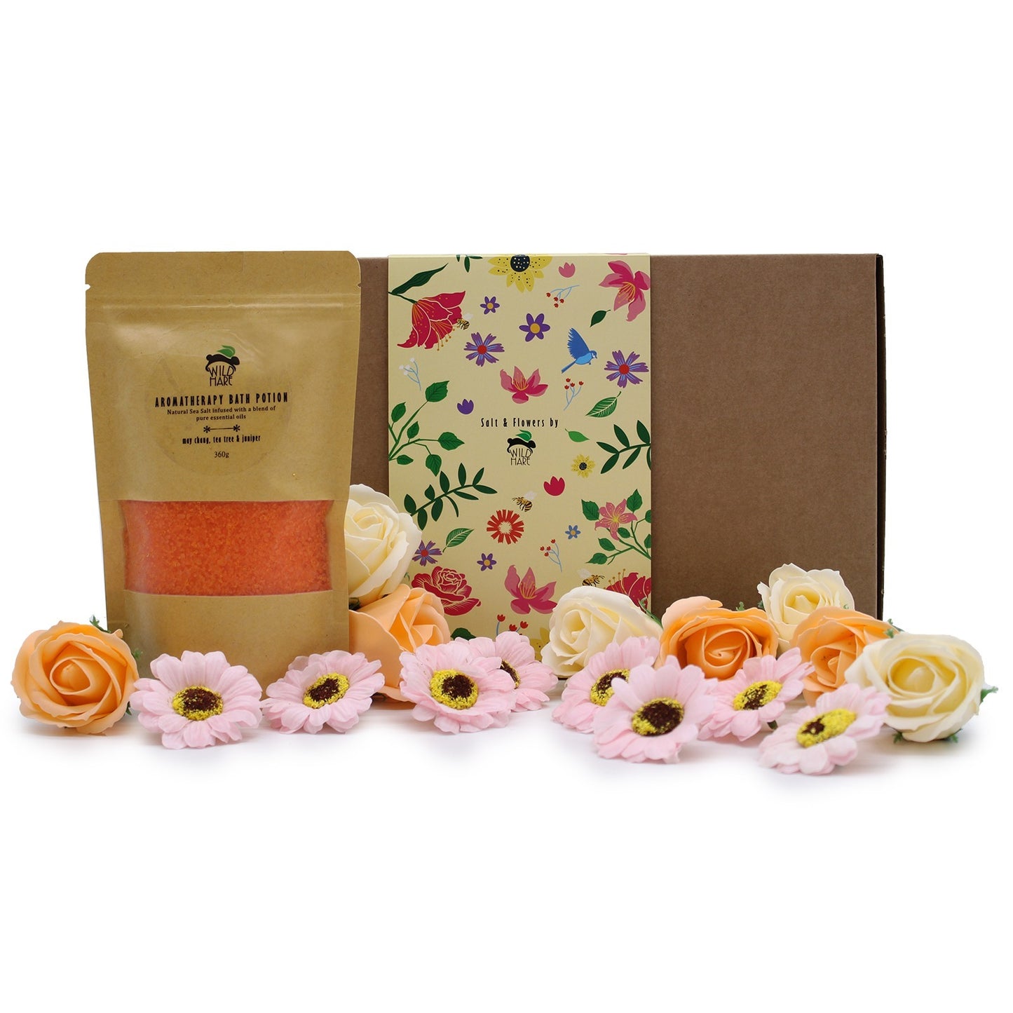Aromatherapy bath salts sit by a floral-themed box, adorned with roses and daisies. Text on the bath salt pouch reads: “AROMATHERAPY BATH POTION Natural Sea Salt infused with a blend of pure essential oils...may chang, tea tree & juniper 360g.” The box reads: “Salt & Flowers by.”