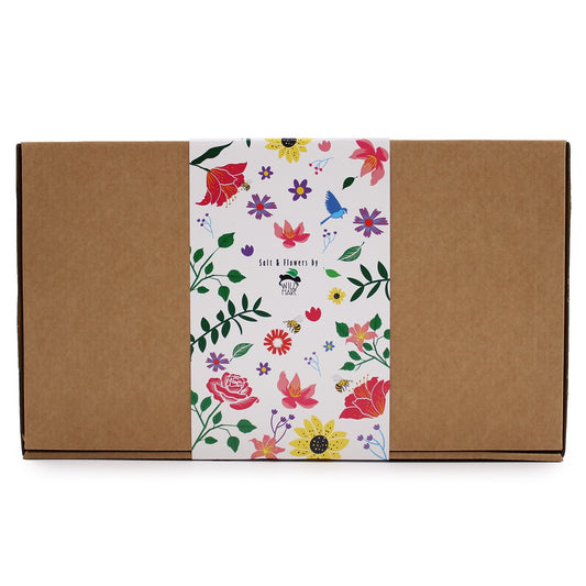 A brown cardboard box has a decorative floral band around it, which is labeled "Salt & Flowers by WILD HARE" with colorful flower and leaf designs.