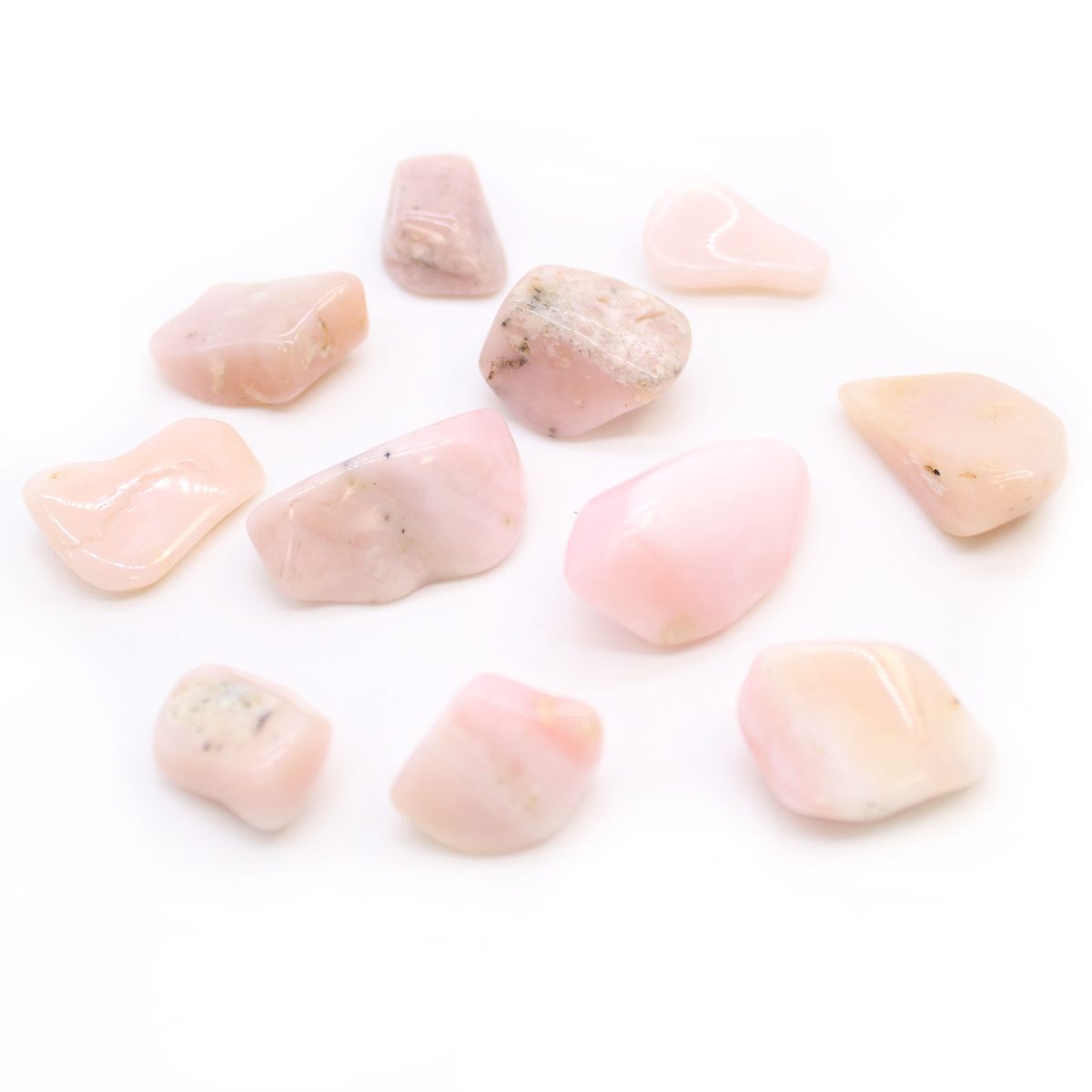 Several tumbled pink opal stones are scattered against a white background.
