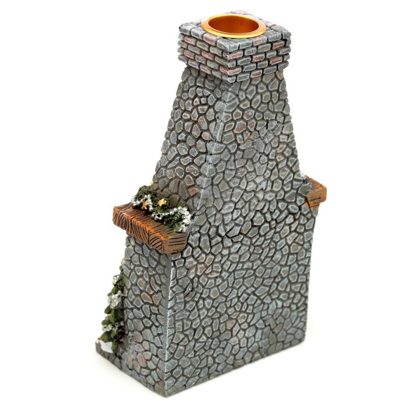 Stone-textured chimney sculpture with a rectangular base and narrower top. It has a small ledge adorned with greenery and lights, against a plain white background.