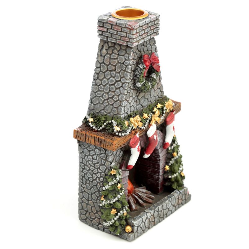 A miniature stone fireplace decorated with Christmas stockings and garlands, features a wreath and bow. The firewood is stacked inside, with a chimney on top, evoking a festive holiday scene.