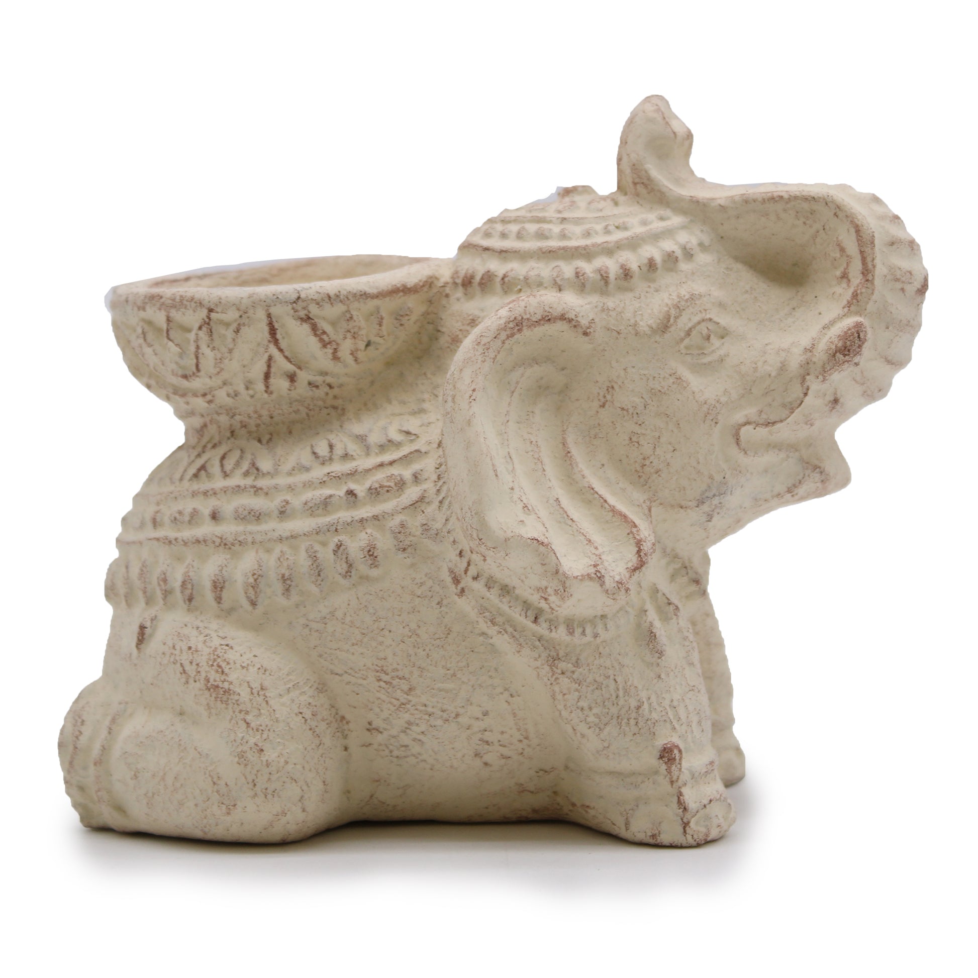 A decorative stone elephant figurine with intricate carvings sits contently, trunk raised. It has a hollow area on its back, likely for holding small items, set against a plain background.