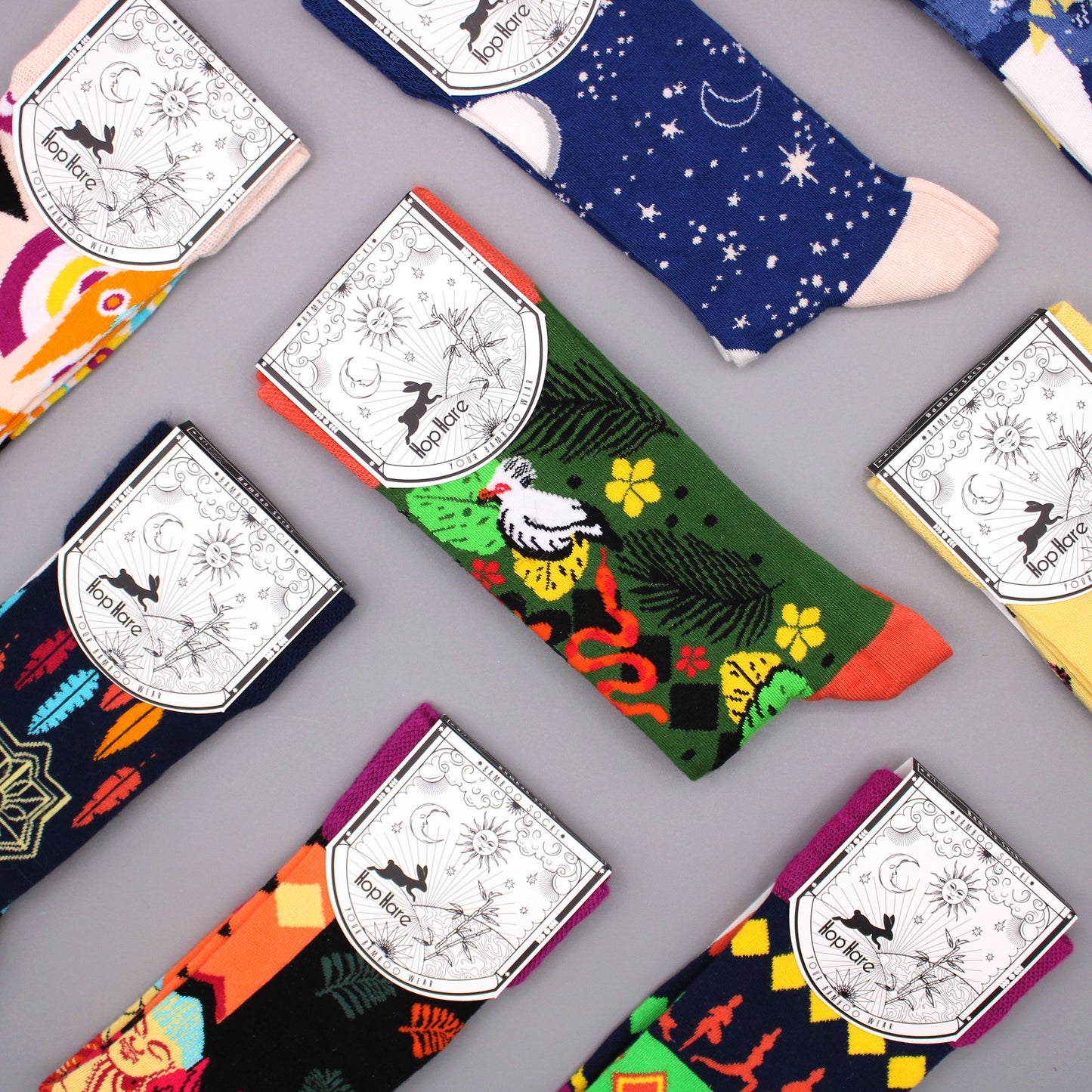 Colorful socks, arranged on a gray surface, display various patterns and are tagged with “Hop Hare Your Bamboo Wear”.