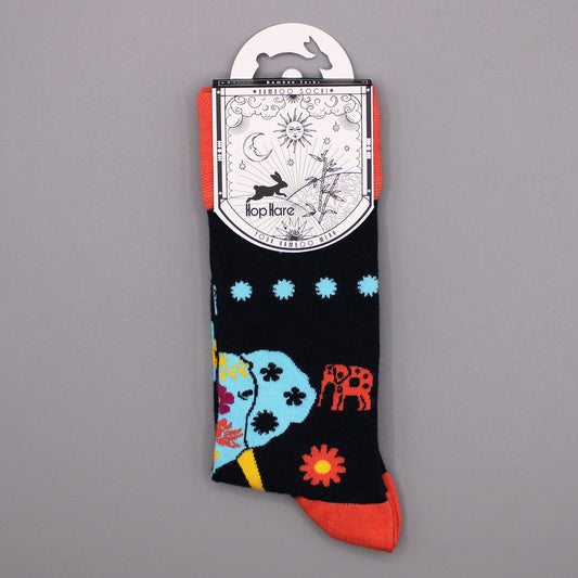 A pair of socks hangs from a tag; the socks feature colorful elephants and flowers on a dark background. The tag shows a rabbit and bamboo; the socks are displayed against a gray backdrop.