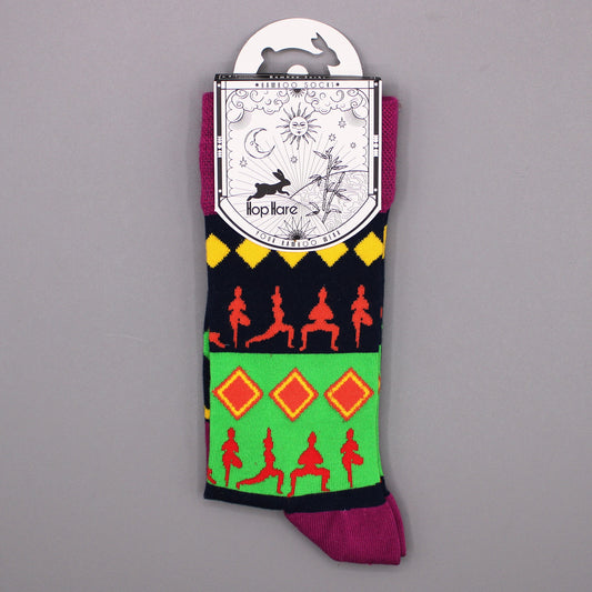 A pair of colorful socks, displaying yoga poses and geometric patterns, hangs from a tag against a gray background. The tag reads: "*BAMBOO SOCKS* Hop Hare YOUR BAMBOO WEAR".