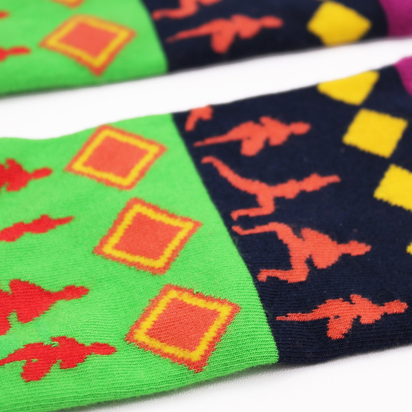 Colorful socks lay on a white background; they are patterned with red, orange, yellow, and green shapes and silhouettes.