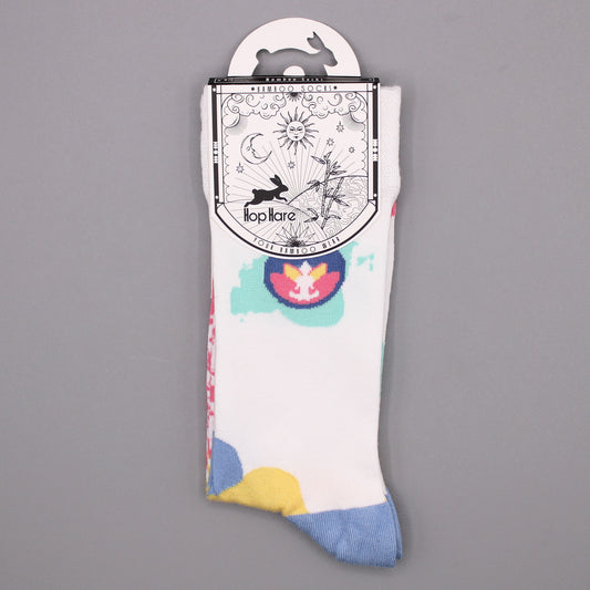 A pair of white bamboo socks, displayed against a grey background, features colorful designs and is presented on a hanger. The tag reads: "Bamboo Socks *BAMBOO SOCKS* Hop Hare YOUR BAMBOO WEAR".