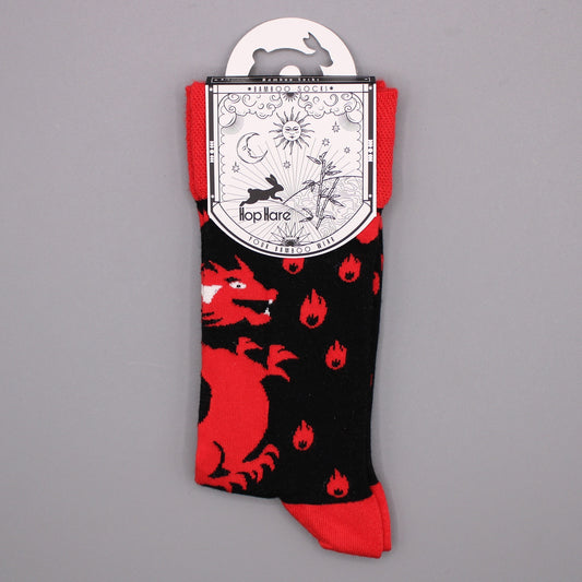 Bamboo socks with a red dragon and flame design are displayed against a gray background. The socks are attached to a card featuring a rabbit, sun, moon, and bamboo.