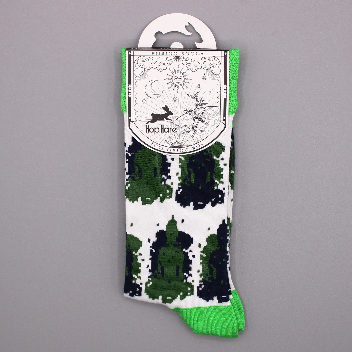 A sock with a green, black, and white pattern hangs from a tag. The tag displays illustrations of a rabbit, sun, moon, bamboo, and the text: "Bamboo Socks," "Hop Hare," and "Your Bamboo Wear."