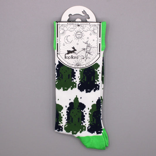 A sock with a green, black, and white pattern hangs from a tag. The tag displays illustrations of a rabbit, sun, moon, bamboo, and the text: "Bamboo Socks," "Hop Hare," and "Your Bamboo Wear."