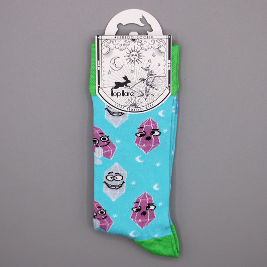 A pair of light-blue socks, featuring cartoon crystals, hangs from a tag against a gray background. The tag reads: "*BAMBOO SOCKS*", a rabbit illustration, "Hop Hare", "YOUR BAMBOO WEAR".