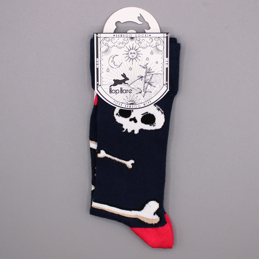 A pair of navy blue socks, featuring skull and crossbones, hangs from a tag against a gray background. The tag reads: "*BAMBOO SOCKS* Hop Hare YOUR BAMBOO WEAR".