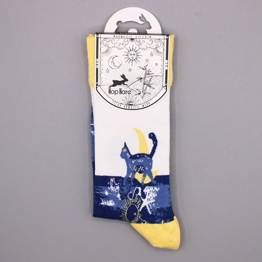 A pair of socks, featuring a cat design and a crescent moon, hangs from a tag against a gray background. The tag reads: *BAMBOO SOCKS*, Hop Hare, YOUR BAMBOO WEAR.