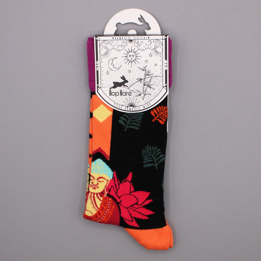 Colorful socks, featuring Buddha and floral patterns, hang from a card against a gray background. The card reads: *BAMBOO SOCKS* Hop Hare YOUR BAMBOO WEAR.