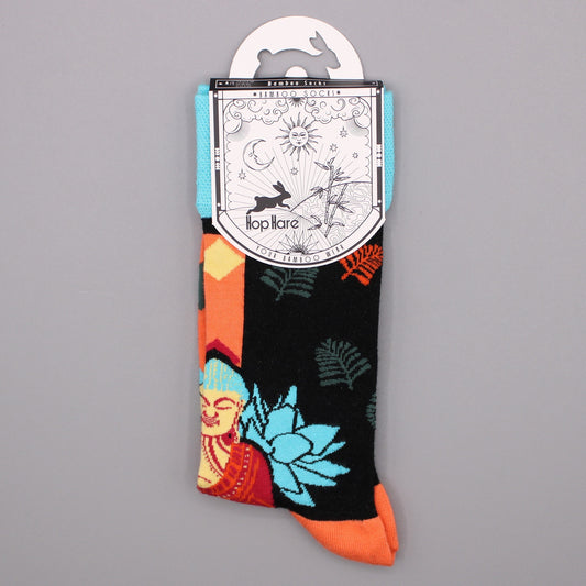 A pair of colorful bamboo socks, displaying a Buddha and floral pattern, hangs from its packaging against a gray background. The packaging depicts a rabbit, sun, moon, and bamboo. M/L 9-12.5 US.