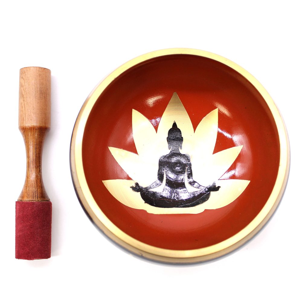 A decorated singing bowl, featuring a black meditating figure over a lotus design, sits beside a wooden mallet with a red grip, on a white background.