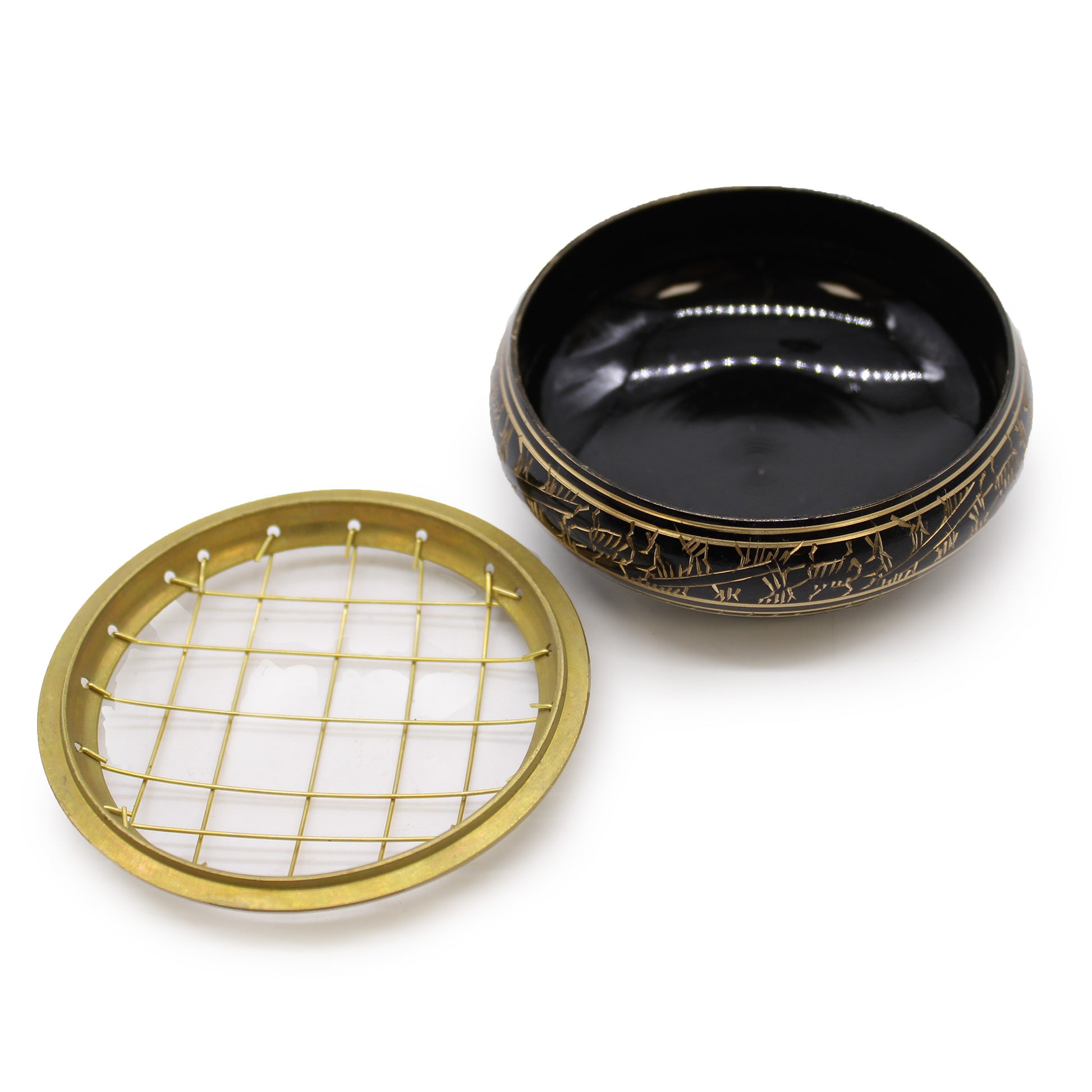 Decorative black and gold wooden bowl, removed lid with intricate gold grid and engraved pattern, set on a smooth white surface.