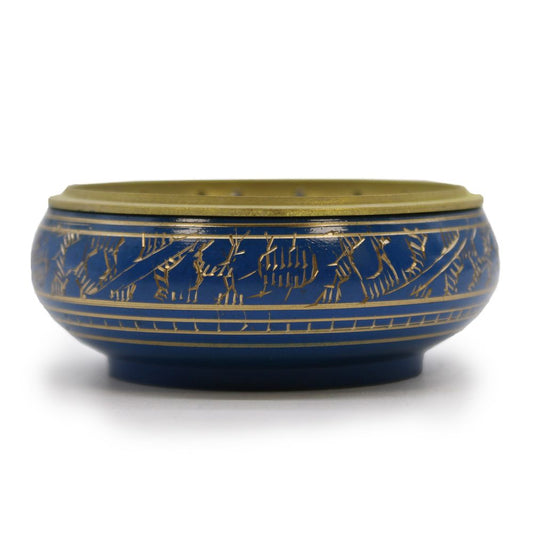 A ceramic pot features intricate gold engravings on a deep blue background, resting on a plain white surface. The pot is rounded with a golden rim at the top.