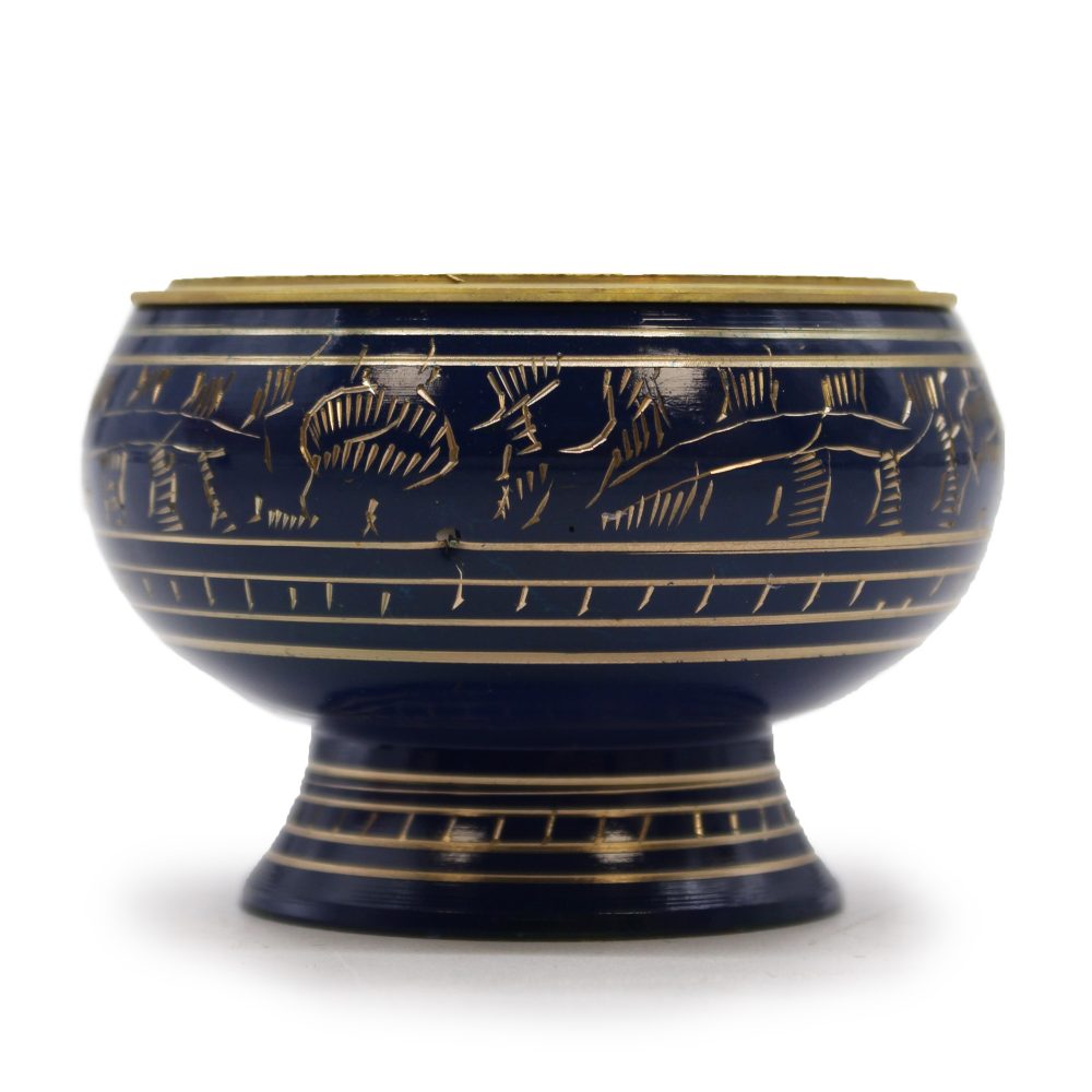 A round, dark blue ceramic bowl with intricate golden etchings of figures and lines sits on a matching pedestal base against a plain white background.