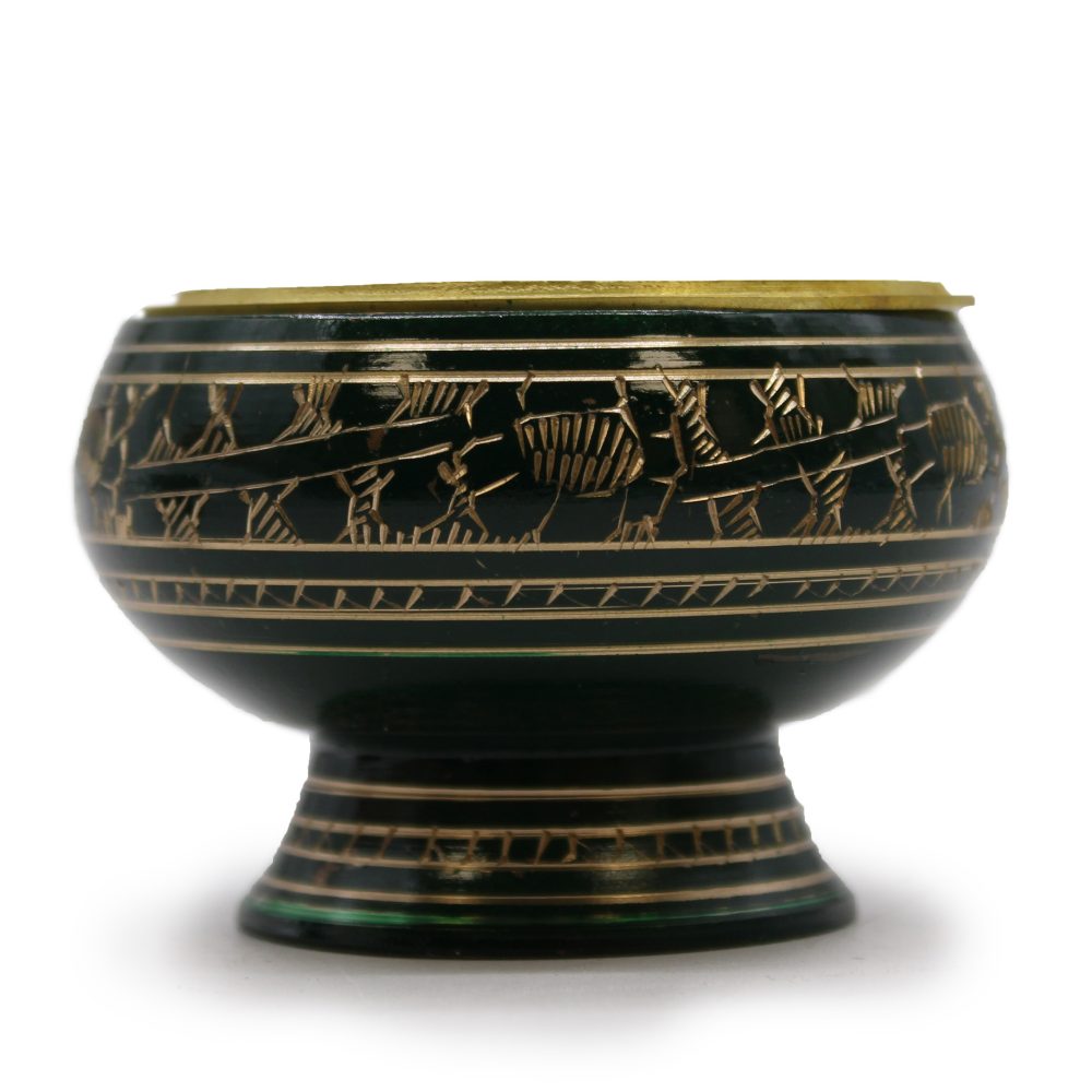 A decorative bowl with intricate gold patterns depicting figures and lines, set on a sturdy base, features detailed carvings on a dark green surface against a plain white background.