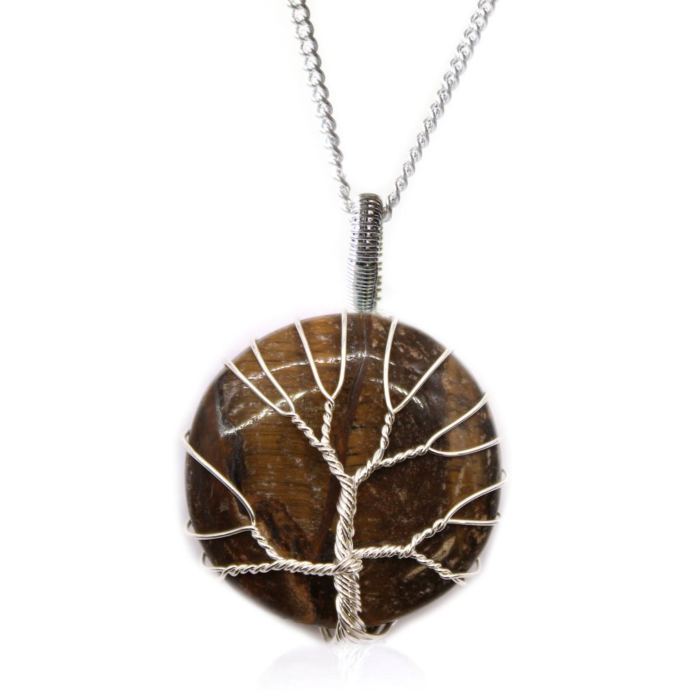 A brown, circular stone pendant, featuring a silver wire "tree," hangs from a delicate silver chain, resting on a white surface.