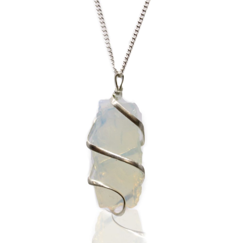 A quartz crystal pendant is wrapped in silver wire and hangs from a chain against a white background, reflecting a faint shadow of the pendant.